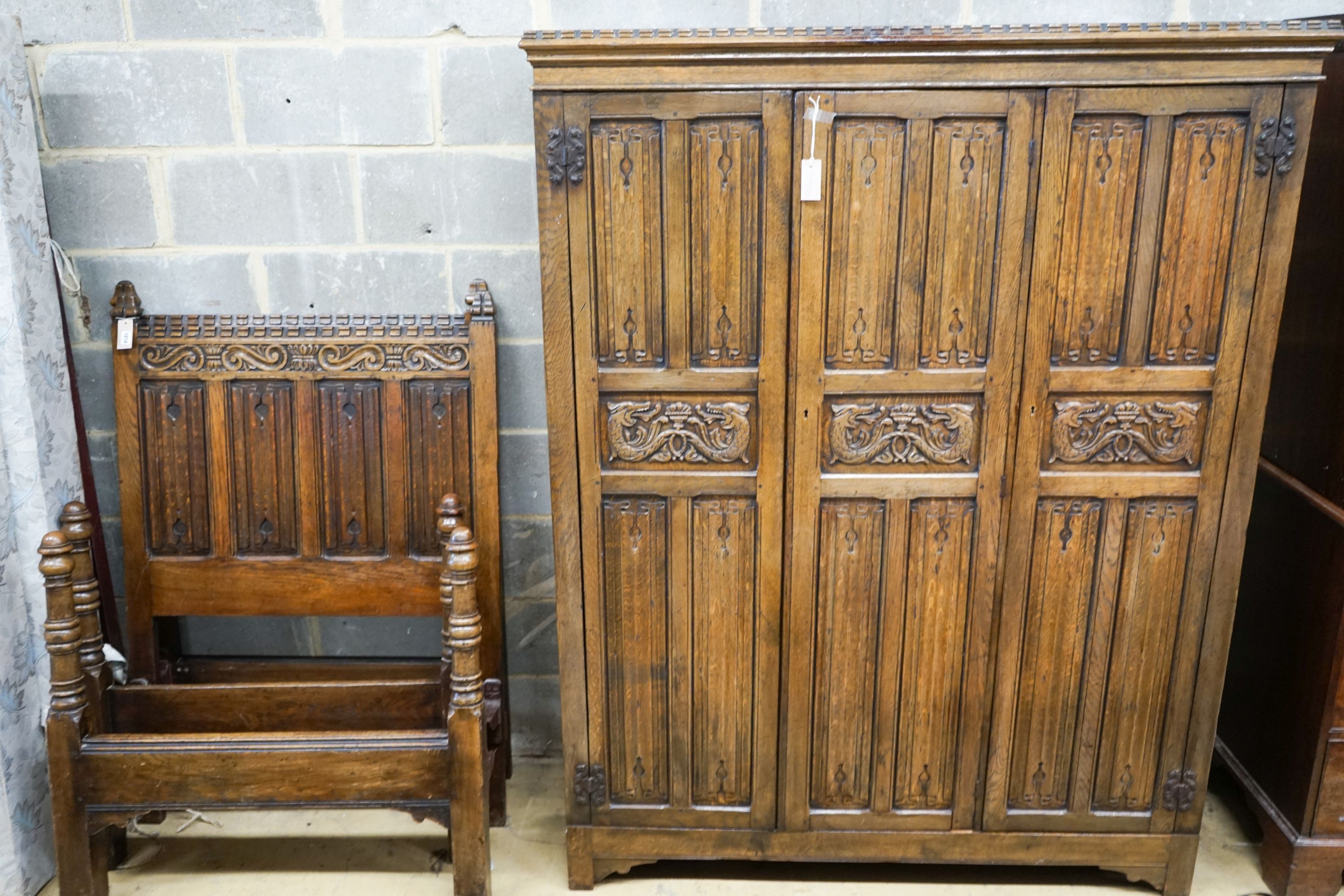 A 17th century style carved and panelled oak triple wardrobe with linenfold decoration, and a pair of early 20th century revival linenfold carved single bedframes, width 91cm, height 130cm